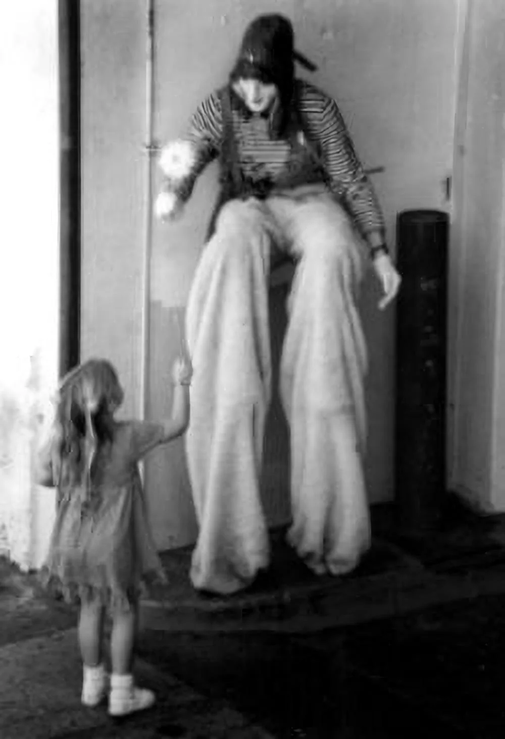 A performer on stilts connecting with a young child